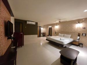 a large bedroom with a large bed and a television at Hotel RNR The Luxury Suits Lodging & Restaurant in Rāichūr