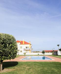 a villa with a swimming pool in front of a house at Casa da Maria - T1 perto da praia do Baleal com piscina in Ferrel