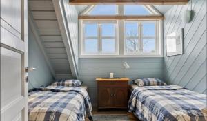 two beds in a attic room with a window at Salteriet in Vinnes