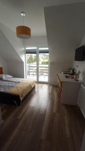 a bedroom with a bed and a desk and a kitchen at Kompas in Krynica Morska