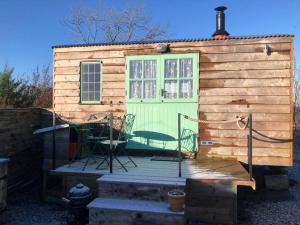 a tiny house with a green door and a chair at Shepherd’s Hut with complete privacy in Bottesford