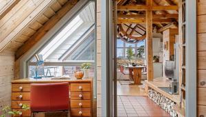 an attic kitchen with a large window and a red chair at Salteriet in Vinnes