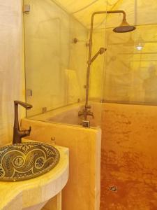ein Bad mit einem Waschbecken und einer Dusche in der Unterkunft Mhamid Luxury Camp in Mhamid