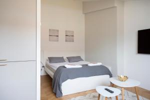 a white bedroom with a bed and two tables at 2ndhomes Ullanlinna Penthouse Apartments 2 in Helsinki