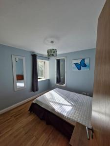 una camera da letto con letto, pareti blu e pavimenti in legno di Excellent location St Anne's Park 2 Bed/Bath Apartment, Dublin 5 a Dublino