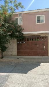 a building with a brown garage door and a tree at Loft o departamento completo #2 in Ciudad Juárez