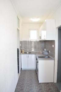 a white kitchen with white cabinets and a sink at Milica Apartments in Sutomore