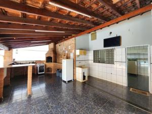 a large room with a kitchen with white tiled walls at Casa com piscina de 2 dormitórios in Ribeirão Preto