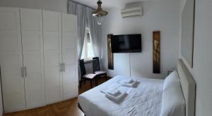 a bedroom with a white bed and a flat screen tv at Appartamento in Villa Naomi in Rome