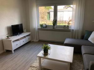 a living room with a couch and a tv and a table at Schön gelegene Ferien-/Pendlerwohnung nahe Rothaarsteig mit guter Anbindung in Haiger