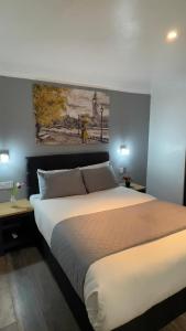 a bedroom with a large bed with a painting on the wall at Pasha Hotel - 3* Boutique Hotel in London