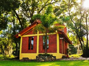 a small red and yellow house with a palm tree at Cabañas del Bosque in San Miguel Regla