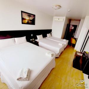 two beds in a hotel room with white sheets at Qallwa Pucallpa in Pucallpa