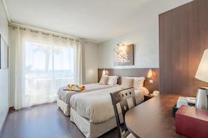 1 dormitorio con 2 camas, mesa y ventana en Hôtel La Plage, en Sainte-Maxime