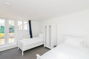 a white bedroom with two beds and a window at May Disc - Long Stay - Contractors in Bristol