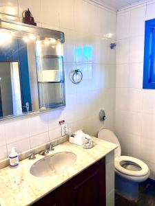a bathroom with a sink and a toilet and a mirror at Casa do canto in Búzios
