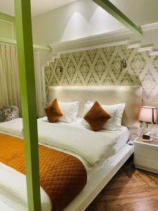 sypialnia z 2 łóżkami z białymi i pomarańczowymi poduszkami w obiekcie Victorian Elegance Luxury Stays w mieście Amritsar