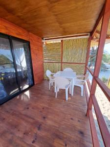 un porche de madera con mesa y sillas. en Cabañas Alta Mar en Guayabas