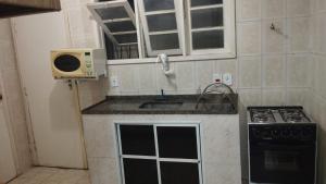 uma pequena cozinha com um lavatório e um fogão em Casa Area Gourmet em Araruama