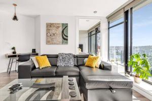 バンクーバーにあるCentral Luxury Apartment with Best City Views!のリビングルーム(黒い革張りのソファ、大きな窓付)
