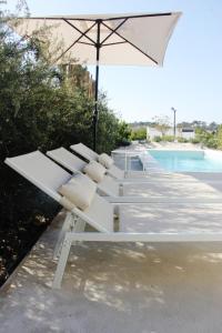 - un banc blanc avec un parasol à côté de la piscine dans l'établissement Casa Menina do Mar in Carvalhal Beach, à Grândola