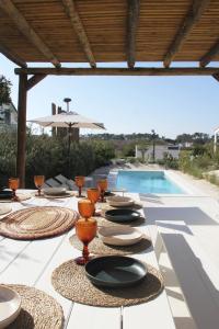 een tafel met borden en kommen naast een zwembad bij Casa Menina do Mar in Carvalhal Beach in Grândola