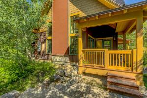 ein Haus mit einer gelben Veranda auf der Vorderseite mit einer Veranda in der Unterkunft Tamarack Ski Resort Townhome - Elegant couple's retreat - Path to chairlift - Golf in Donnelly