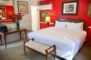 a bedroom with red walls and a white bed and a table at Yosemite Bug Rustic Mountain Resort in Midpines