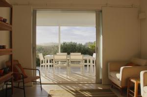 d'un salon avec une table, des chaises et une porte coulissante en verre. dans l'établissement Casa Menina do Mar in Carvalhal Beach, à Grândola