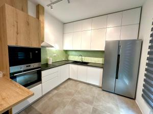 a kitchen with white cabinets and a stainless steel refrigerator at Queen’s Luxury Vila 111/A in Dhërmi