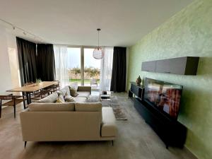 a living room with a couch and a tv and a table at Queen’s Luxury Vila 111/A in Dhërmi