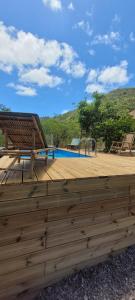 een houten terras naast een zwembad bij VILLA CAJOU DESIRADE in Baie Mahault