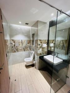 La salle de bains est pourvue de toilettes et d'une douche en verre. dans l'établissement Luxury Studios Key 5 - 2 BHK Fully Furnished Apartment, à Gurgaon