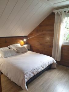a bedroom with a large white bed with wooden walls at Porte de Mafate - Grand Ilet in Salazie