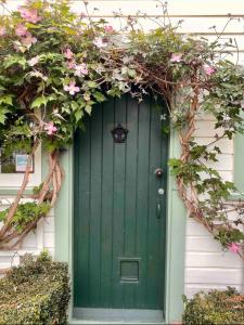 a green door on a house with pink flowers at Green Door Cottage in Greytown