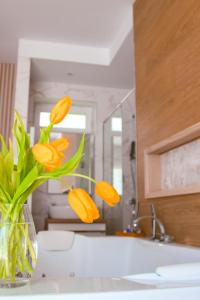 a vase filled with yellow flowers sitting on a sink at TWIN prémium apartman in Tihany