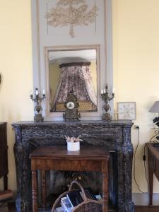 une cheminée avec un miroir et une horloge. dans l'établissement Château de la Mothe, à Saint-Sulpice-en-Pareds