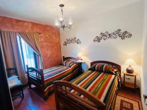 1 dormitorio con 2 camas, silla y ventana en Paseo del Obispo Apartamento A3, en Antigua Guatemala