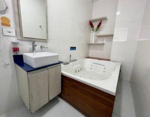 a white bathroom with a tub and a sink at Hotel Sixtina Plaza Medellin in Medellín