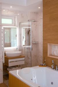 a bathroom with a tub and a shower and a sink at TWIN prémium apartman in Tihany