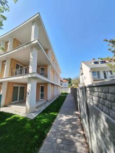 a building with a stone wall next to a sidewalk at Orchidea apartman in Balatonalmádi