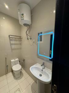 a bathroom with a toilet and a sink and a mirror at أجنحة دارنـــــا للـــشقق الــمــفــروشــة in Abha