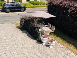 una mesa y sillas con sombrilla y flores en Isa's Appartement en Lommel