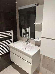 een badkamer met een witte wastafel en een spiegel bij La Cascade 1 in Oran