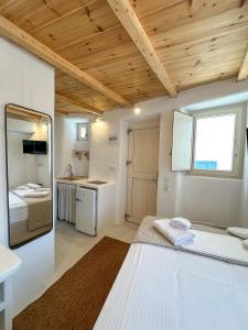 a bedroom with a large white bed and a kitchen at Lythi Kythnos in Kithnos