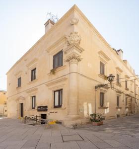 - un grand bâtiment en pierre avec des chaises jaunes devant dans l'établissement Palazzo Personè Dimora Storica, à Lecce