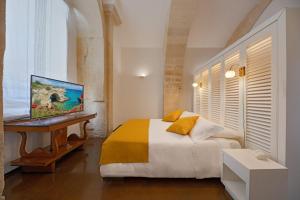 a bedroom with a bed and a desk with a television at Palazzo Personè Dimora Storica in Lecce