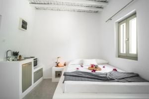 a white bedroom with a bed and a window at Armonia Guesthouse close to Mykonos town in Dexamenes