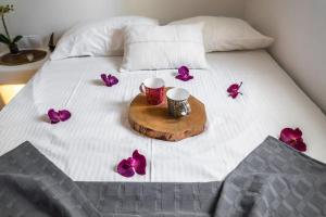 a bed with two cups and purple flowers on it at Armonia Guesthouse close to Mykonos town in Dexamenes