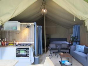 a tent with a kitchen and a living room at Luxe safaritent op Landgoed de Leijen in Hensbroek